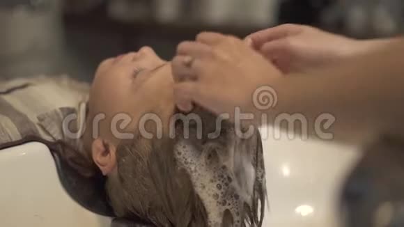 理发师用洗发水在理发店给小男孩洗头和头发把洗头贴到男孩面前视频的预览图