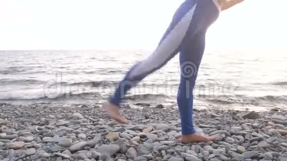 女孩正在做运动在海洋背景上的呼吸练习中腿抬起身体弯曲腿特写视频的预览图