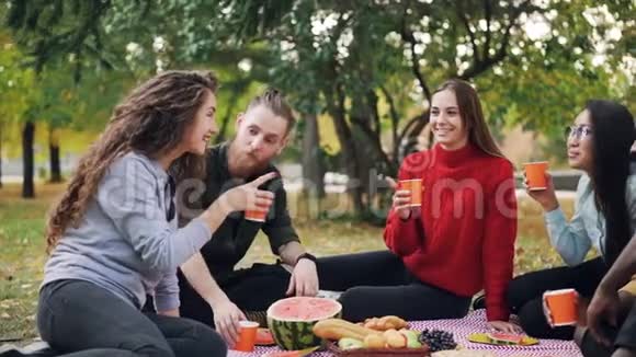 快乐的年轻人慢动作多民族的人群喝着饮料碰杯然后坐在舒适的地方喝酒视频的预览图