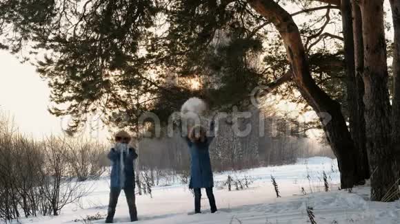 穿着蓝色羽绒服的男人和女人在冬天的森林里扔雪微笑正面观点视频的预览图