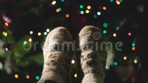 穿暖针织毛袜的女人腿的特写圣诞树旁边有一个装饰品视频的预览图
