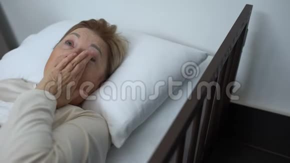 沮丧的老病人擦拭躺在病床上的眼泪志愿者支持女士视频的预览图
