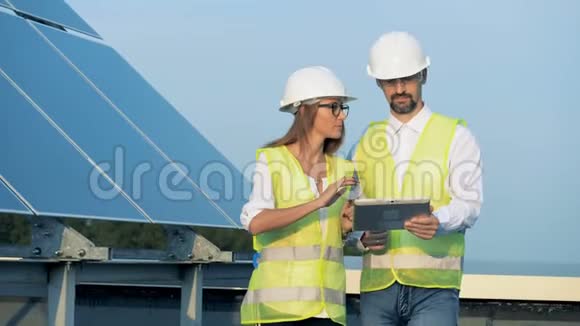 可再生能源概念两名能源学员工正带着平板电脑沿着太阳能建筑行走视频的预览图