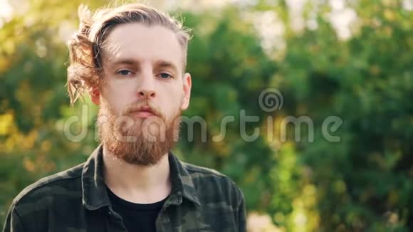 秋日站在公园里看着一个长胡子身穿军服的严肃青年的慢镜头肖像视频的预览图