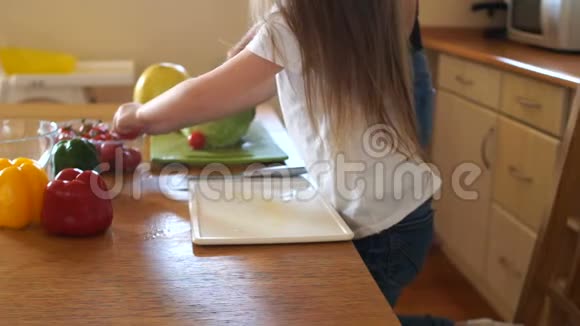 一个漂亮的小女孩第一次用刀切樱桃番茄妈妈帮助女孩教她如何正确视频的预览图