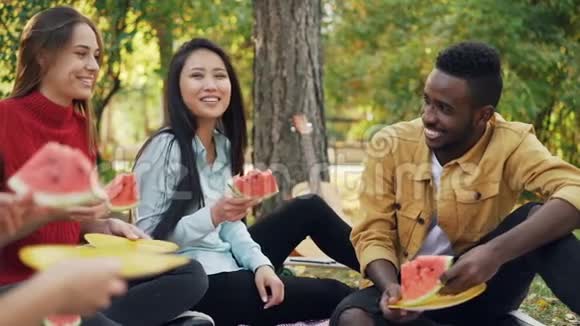 欢快的年轻人在秋天的公园里吃西瓜谈笑风生友谊视频的预览图