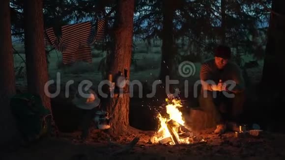 雄性徒步旅行者在森林营地的篝火旁休息户外娱乐视频的预览图