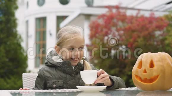 小女孩喝着茶对着南瓜灯微笑万圣节游戏视频的预览图