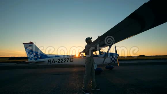 专业飞行员检查飞机的机翼一个男人看着翅膀站在跑道上检查它们视频的预览图