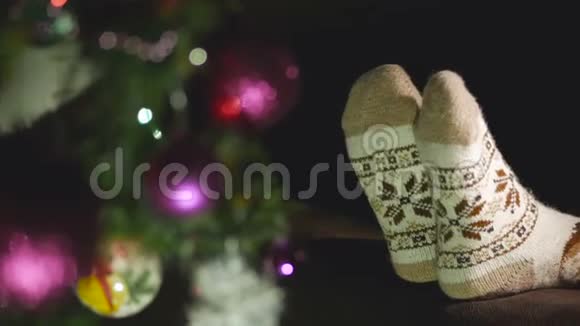 穿暖针织毛袜的女人腿的特写圣诞树旁边有一个装饰品视频的预览图