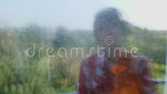 在窗户玻璃反射微笑的女人戴着耳机戴着手套喷洒清洁产品清洁窗户视频的预览图