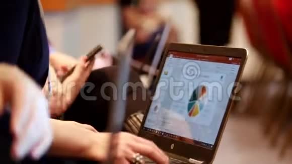 商业概念大厅里的人坐在手机和笔记本电脑里看着屏幕上的时间表视频的预览图