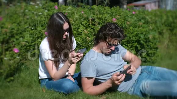 年轻夫妇在公园里休息看着手机玩视频的预览图