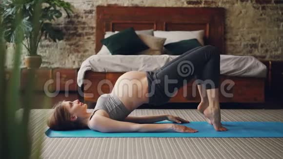 运动怀孕的女孩正在现代阁楼风格的卧室里在明亮的瑜伽垫上练习健身运动健康生活方式视频的预览图