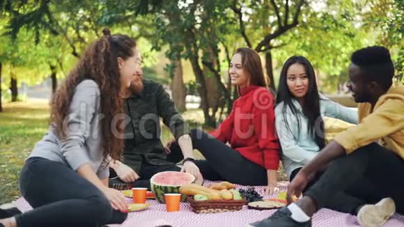 在城市公园野餐时快乐的朋友非裔美国人和高加索人的慢动作友谊视频的预览图