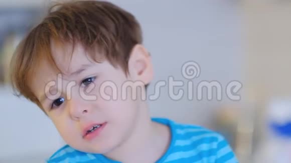 伤心的脸男孩三岁坐在厨房里对着镜头说话视频的预览图