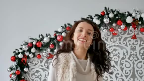美丽卷曲的黑发在圣诞装饰背景下摇着头发在镜头前笑视频的预览图