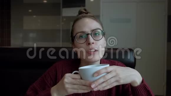 可爱的戴着眼镜的年轻女人坐在咖啡馆里和别人说话视频的预览图