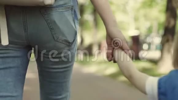 一位年轻的母亲和她的小儿子一起在户外散步那个女人牵着男孩的手视频的预览图