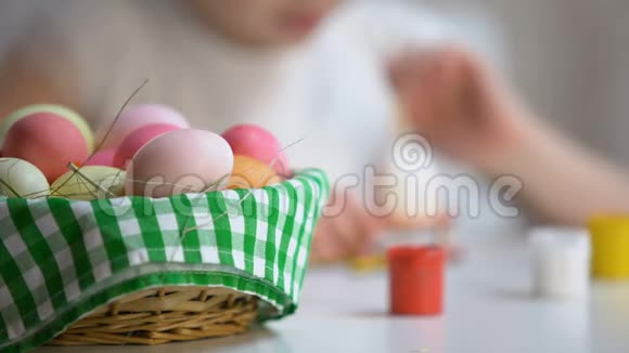 有创意的小女孩用刷子画蛋复活节篮子在桌子上节日视频的预览图