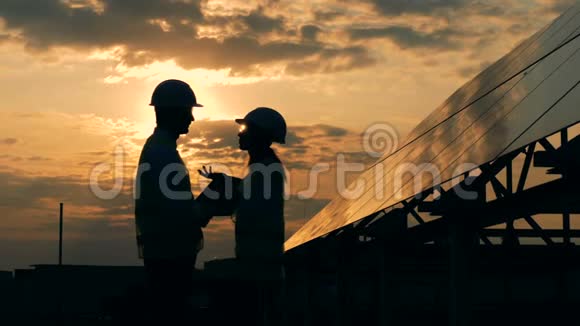 一位女工程师和一位男工程师在太阳能电池板附近的夕阳下交谈替代能源概念视频的预览图