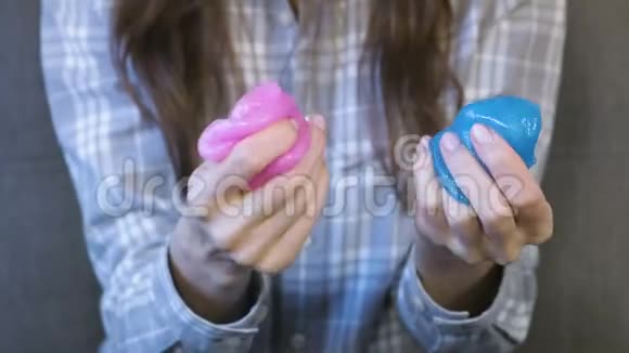 女人双手揉捏挤压和伸展一个粉红色和蓝色的黏液女人玩弄黏液视频的预览图
