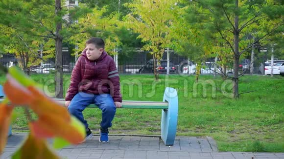 快乐的男孩坐在公园的长凳上在公园里笑慢节奏视频的预览图