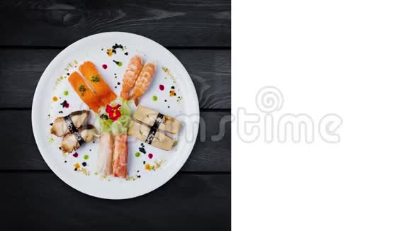 日本菜旋转生鱼片设置在白色圆板上装饰有小花俯视黑色木制视频的预览图