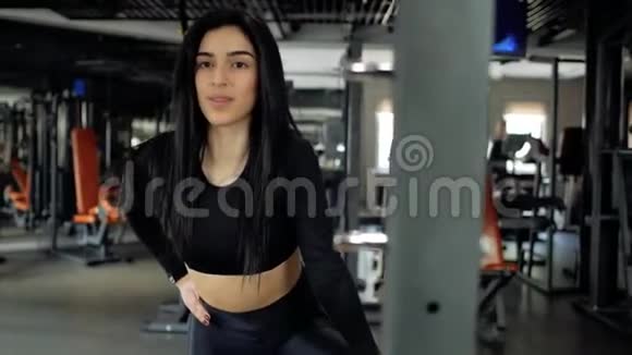 漂亮的黑发女孩穿着黑色紧身裤在健身房做热身运动年轻女孩伸展身体视频的预览图