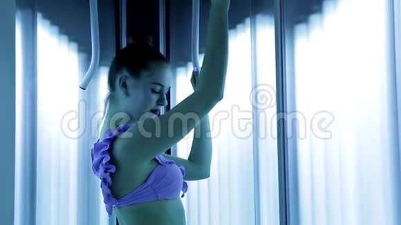一个美丽的女孩一个健康的身体站在水疗中心的日光浴室有一个美丽的身材谭皮肤视频的预览图