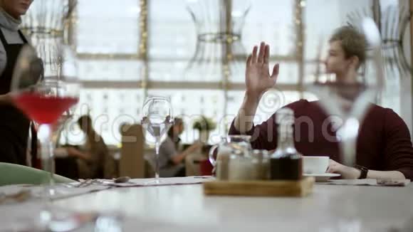 男人坐在餐厅的桌子旁看着账单用卡片付款穿围裙的服务员拿着候机厅视频的预览图