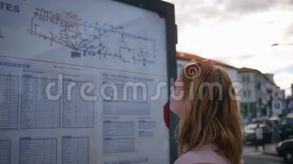 游客看着街道上的公共汽车时间表视频的预览图
