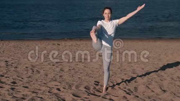 女人在城市河边的海滩上伸展瑜伽美丽的城市景色乌蒂塔哈斯塔帕丹古什萨纳的姿势视频的预览图