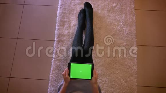 年轻女性青少年在平板电脑上玩绿色屏幕电子游戏的特写镜头穿着可爱袜子的女孩腿视频的预览图