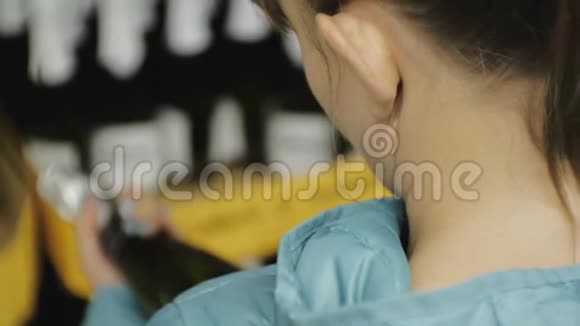 超市里的女人穿着蓝色夹克的白种人年轻女性的特写镜头在黑暗的瓶子上看着标签选择视频的预览图