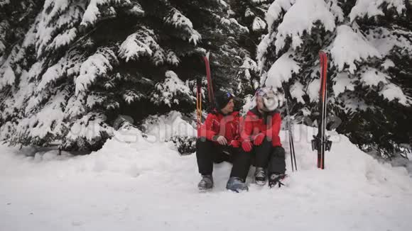 爱的一对夫妇在滑雪场坐在松树下与他们交谈愉快视频的预览图