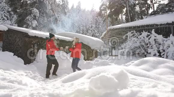 快乐的一对相爱的夫妇在冬天在森林旅馆附近闲逛幸福的家庭在天空中飞雪视频的预览图