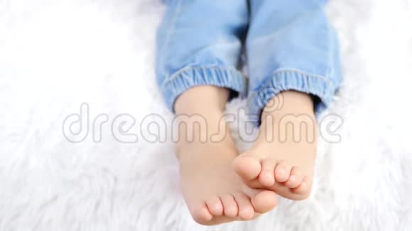 婴儿光着脚无忧无虑地躺在沙发上不知名的孩子赤脚聊天特写镜头视频的预览图