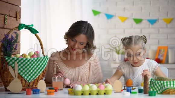 女儿和母亲在复活节彩蛋上涂上五颜六色的染料准备节日视频的预览图