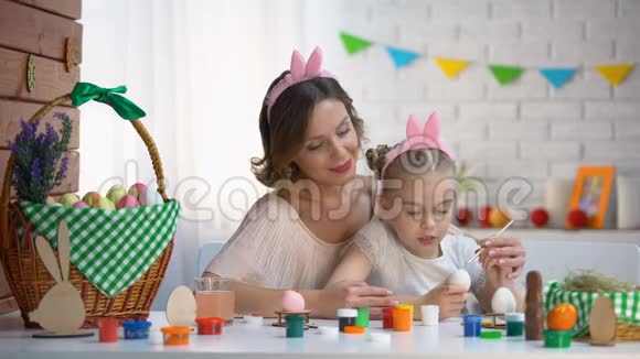 妈妈教女儿装饰鸡蛋一家人戴着可爱的头巾坐在桌子上视频的预览图