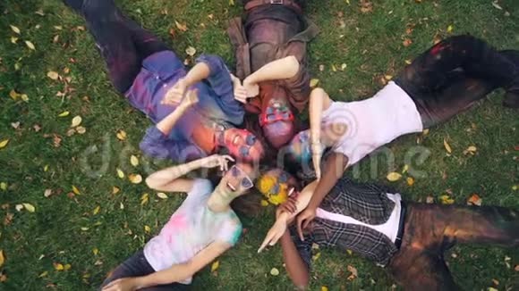 慢动作放大轻松的青春画着的脸躺在草地上伸手拿起相机双手移动微笑着视频的预览图