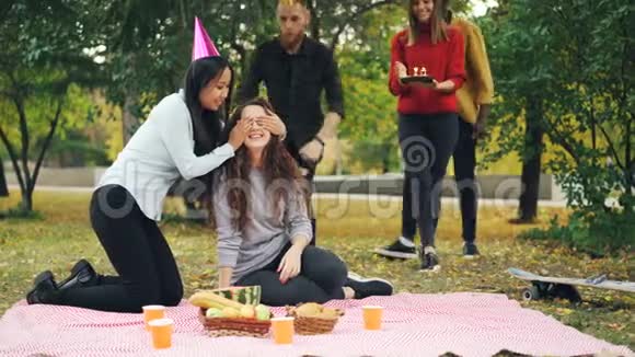 3年轻人祝贺女孩过生日带着蛋糕拥抱亲吻她女人正在吹蜡烛视频的预览图