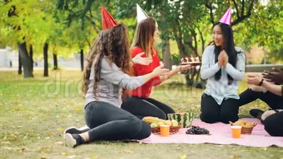 朋友们祝贺亚洲女人生日送蛋糕给她惊喜女孩吹蜡烛微笑着视频的预览图