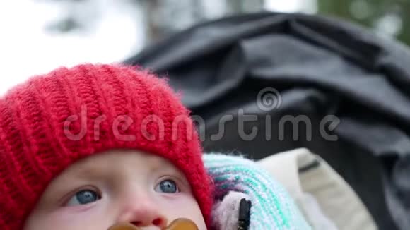 秋天一个戴着红色针织帽子的孩子和一个坐在轮椅上的奶嘴视频的预览图
