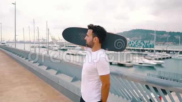 滑板运动员站在现代化的城市露台上与滑板视频的预览图