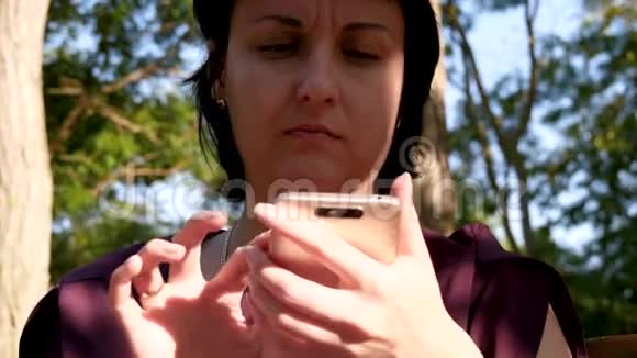 公园里一个女孩用智能手机在社交网络上交流的肖像视频的预览图