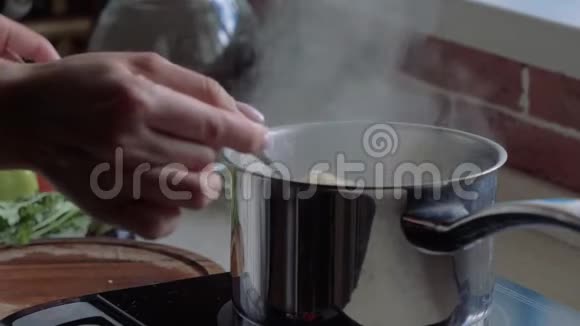 锅在厨房的炉子上女手催粥沸水上升蒸汽视频的预览图
