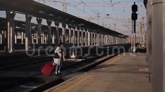 三个女人拿着手提箱在火车站的站台上交谈视频的预览图