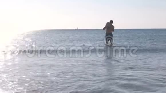 爸爸和儿子在日落时一起在海水中玩耍在海里游泳视频的预览图