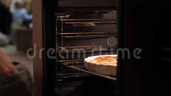 女孩从烤箱里拿出一个节日蛋糕放在桌子上女人手拿厨房手套把披萨从烤箱里拿出来视频的预览图